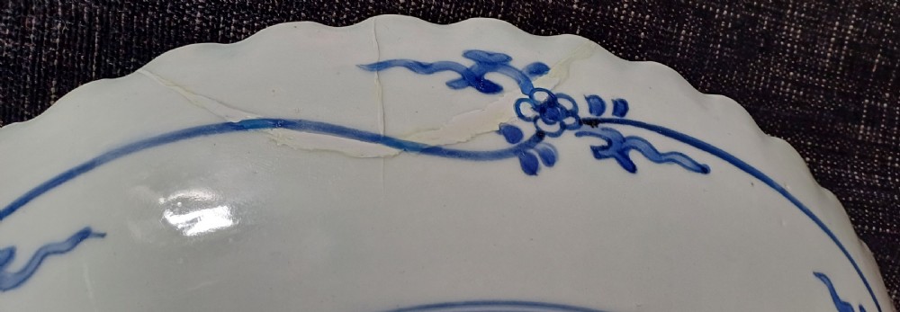 A large round Japanese Arita blue and white porcelain charger with a scalloped rim, hand-painted birds, flowers, and dense scrolling leaf borders. View V