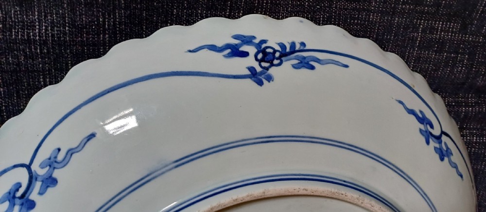 A large round Japanese Arita blue and white porcelain charger with a scalloped rim, hand-painted birds, flowers, and dense scrolling leaf borders. View VIII