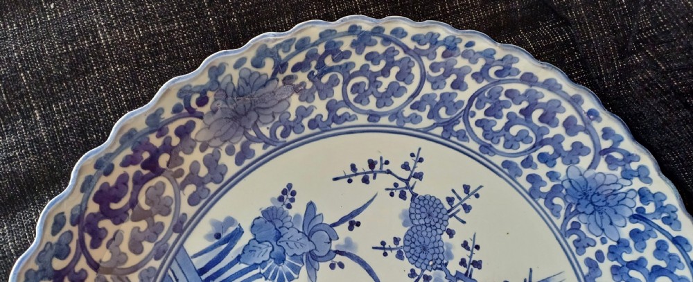 A large round Japanese Arita blue and white porcelain charger with a scalloped rim, hand-painted birds, flowers, and dense scrolling leaf borders. View XII