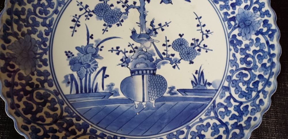 A large round Japanese Arita blue and white porcelain charger with a scalloped rim, hand-painted birds, flowers, and dense scrolling leaf borders. View XIV