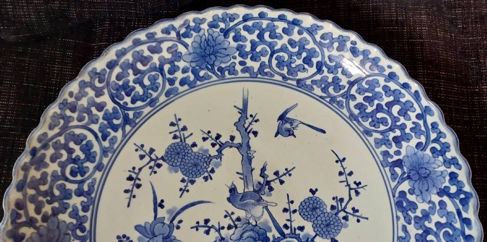 A large round Japanese Arita blue and white porcelain charger with a scalloped rim, hand-painted birds, flowers, and dense scrolling leaf borders. View XV