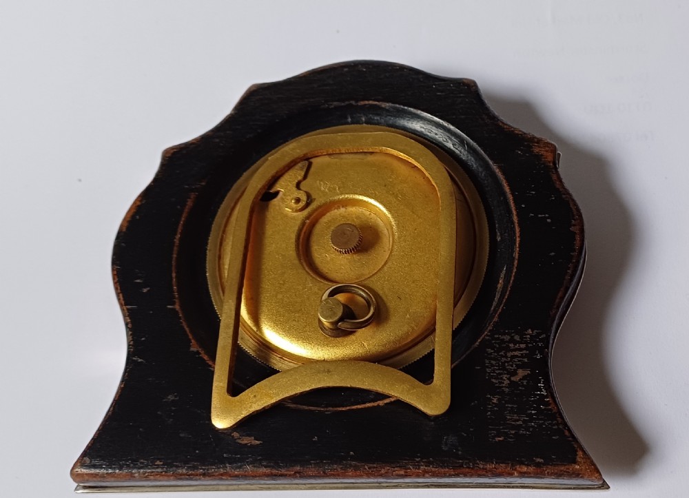 An Art Deco engine-turned silver strut desk clock featuring a shaped outline, circular dial with Arabic numerals, and an engraved circular plaque dated 1927. View X
