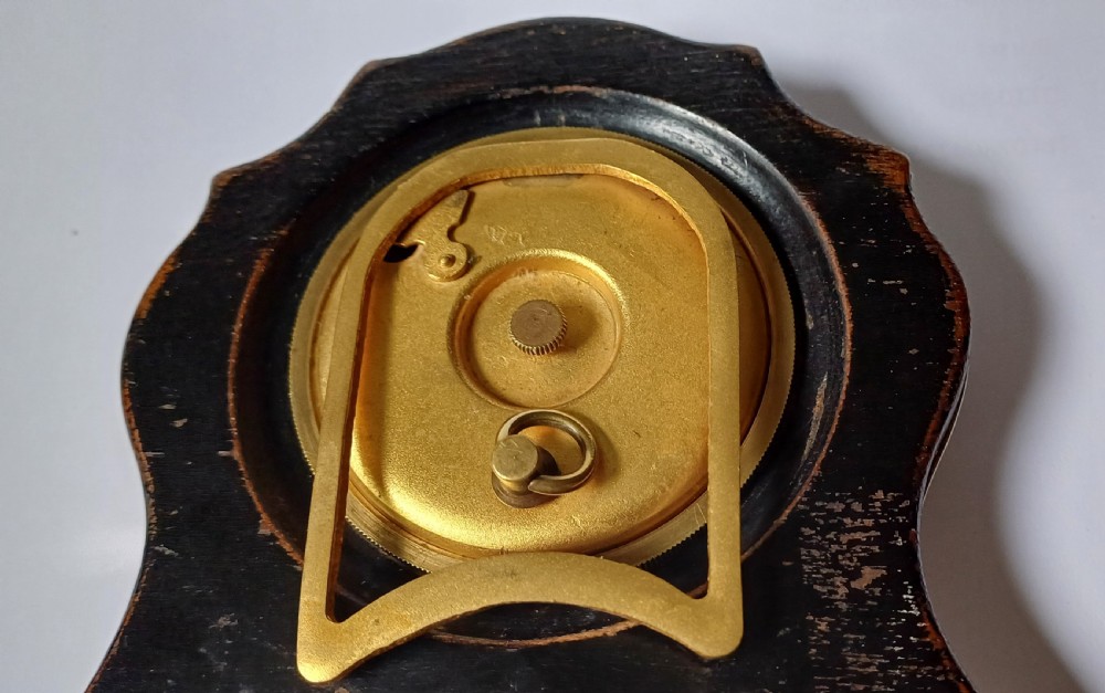 An Art Deco engine-turned silver strut desk clock featuring a shaped outline, circular dial with Arabic numerals, and an engraved circular plaque dated 1927. View XI
