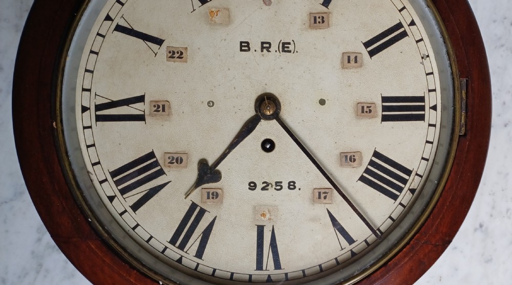 An early 20th-century round mahogany railway wall clock featuring an off-white dial with Roman numerals, secondary 24-hour markings, and B.R.(E.) lettering. View VII