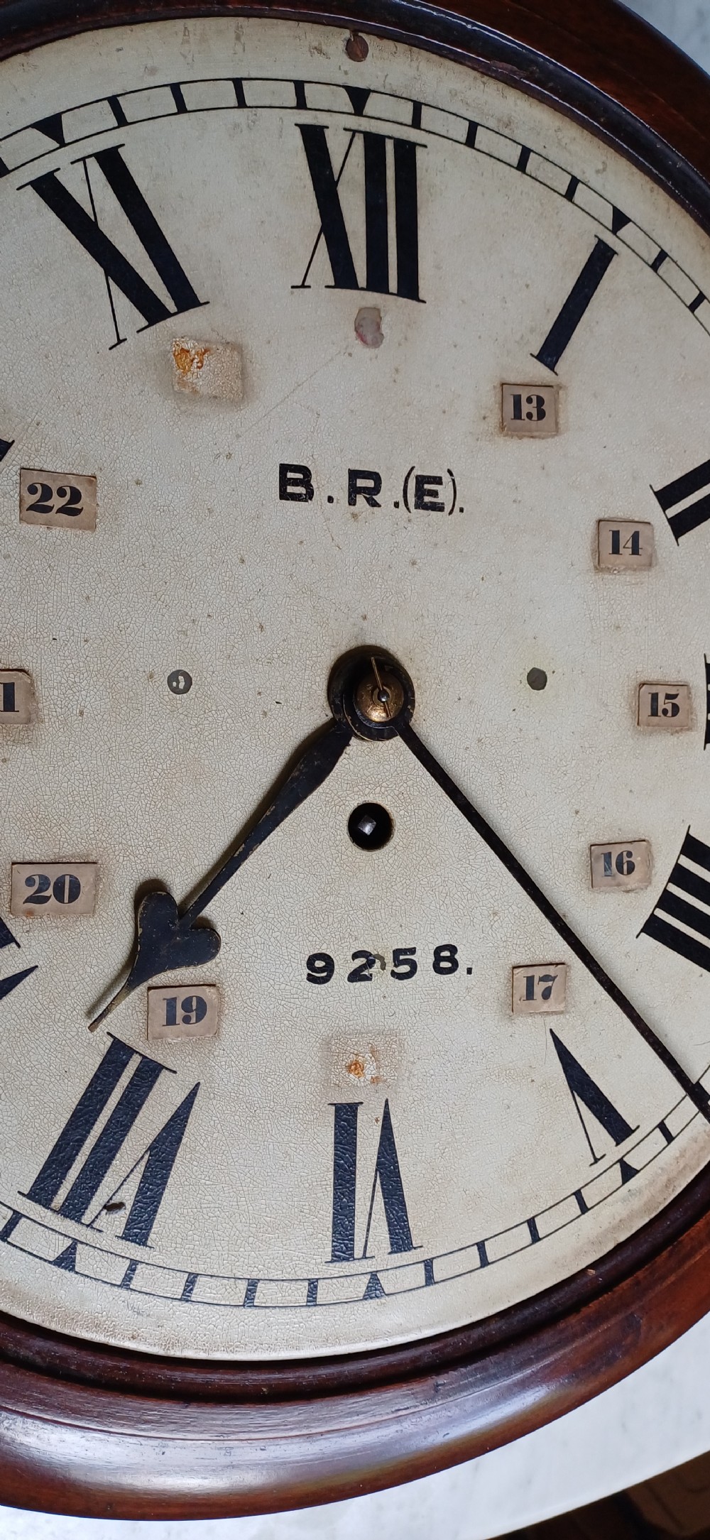 An early 20th-century round mahogany railway wall clock featuring an off-white dial with Roman numerals, secondary 24-hour markings, and B.R.(E.) lettering. View XIII
