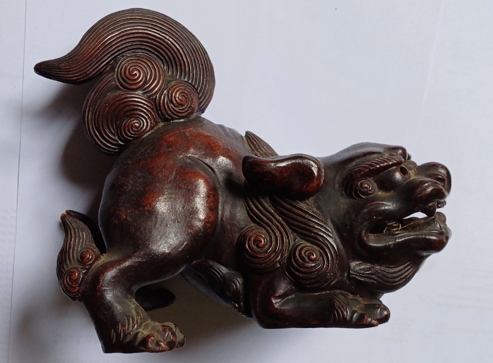 A dark brown Japanese Bizen stoneware Shishi lion dog sculpture with swirling carved details on its mane and tail.