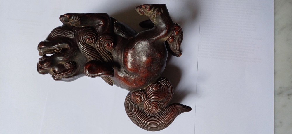 A dark brown Japanese Bizen stoneware Shishi lion dog sculpture with swirling carved details on its mane and tail. View IV