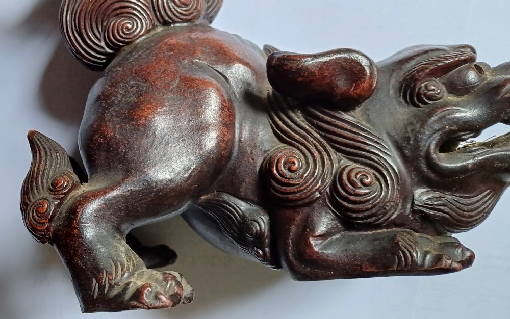 A dark brown Japanese Bizen stoneware Shishi lion dog sculpture with swirling carved details on its mane and tail. View IX