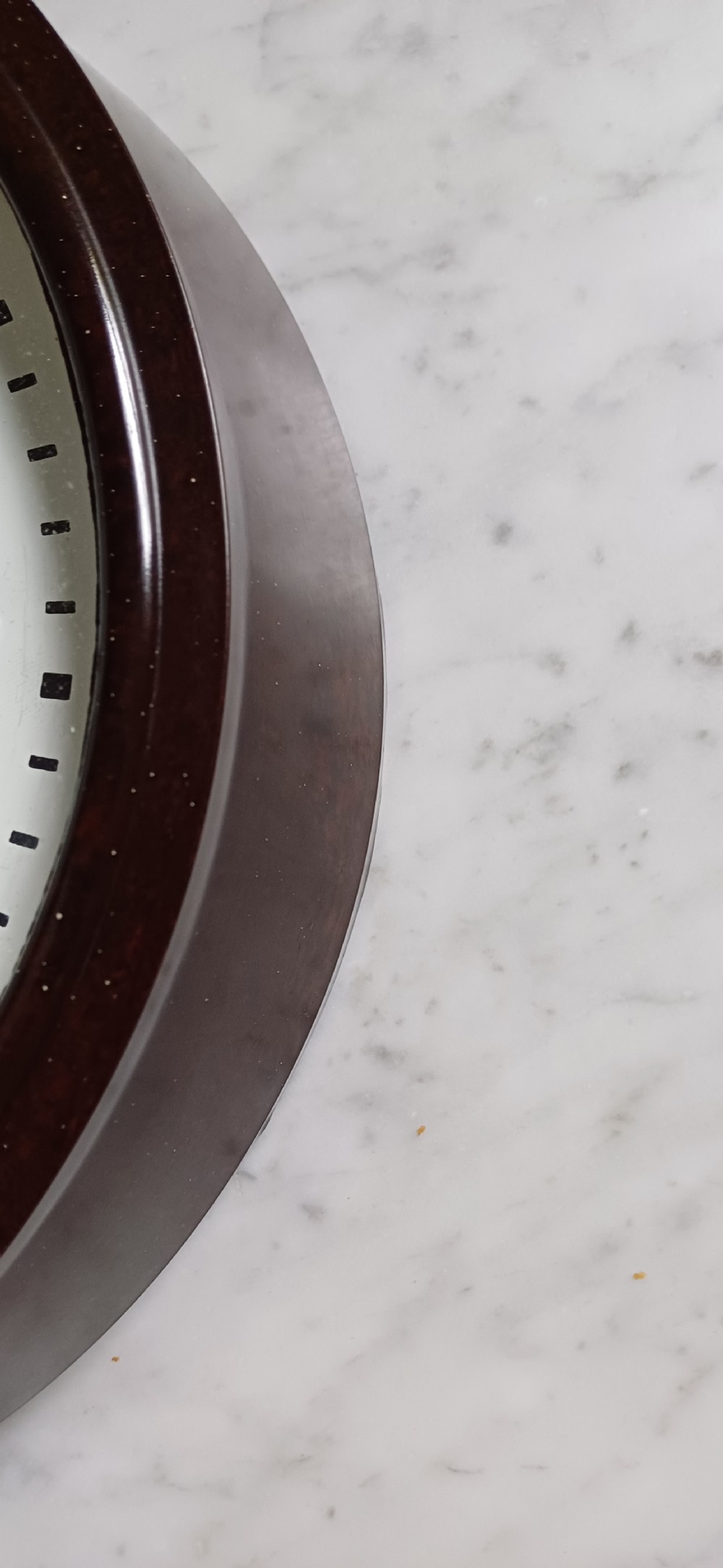 A circular mid-century wall clock featuring a moulded dark brown Bakelite case, a white dial with black Arabic numerals, and dark hands. View XI