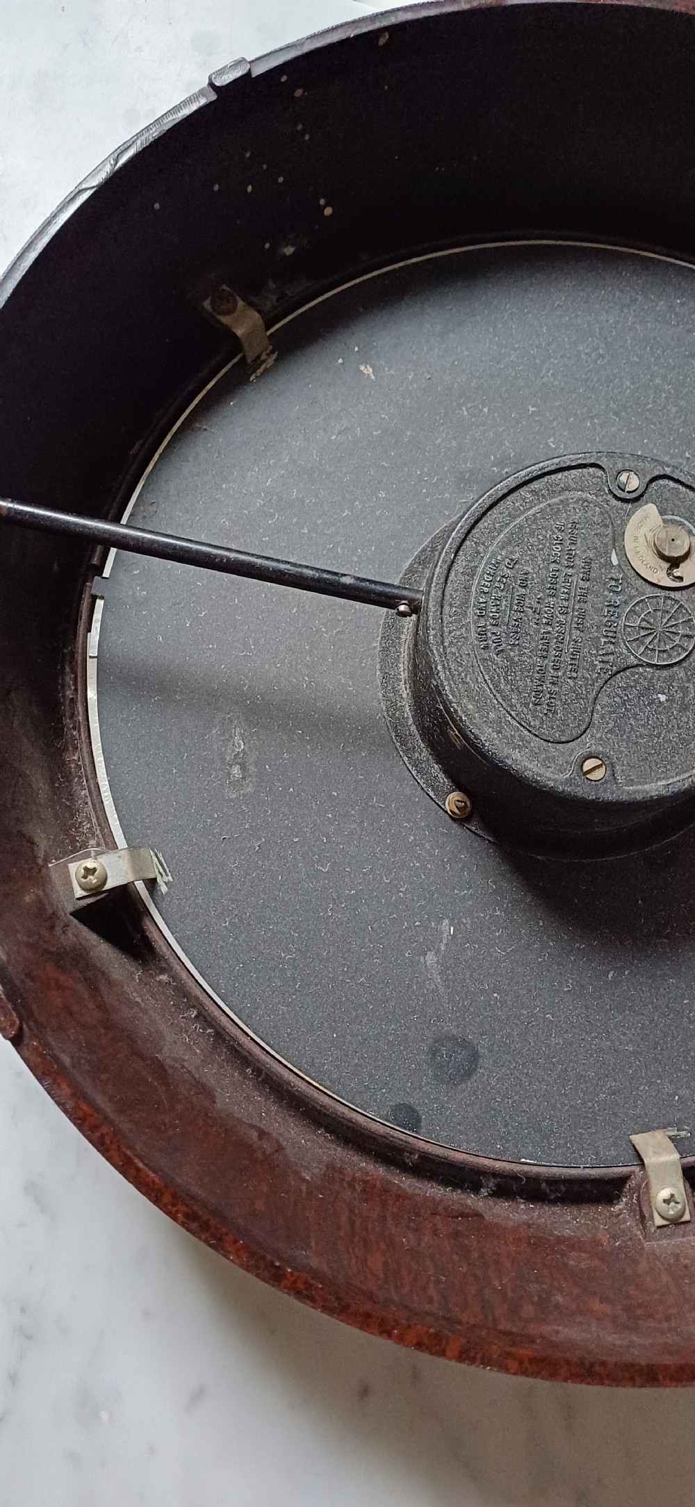 A circular mid-century wall clock featuring a moulded dark brown Bakelite case, a white dial with black Arabic numerals, and dark hands. View XVIII