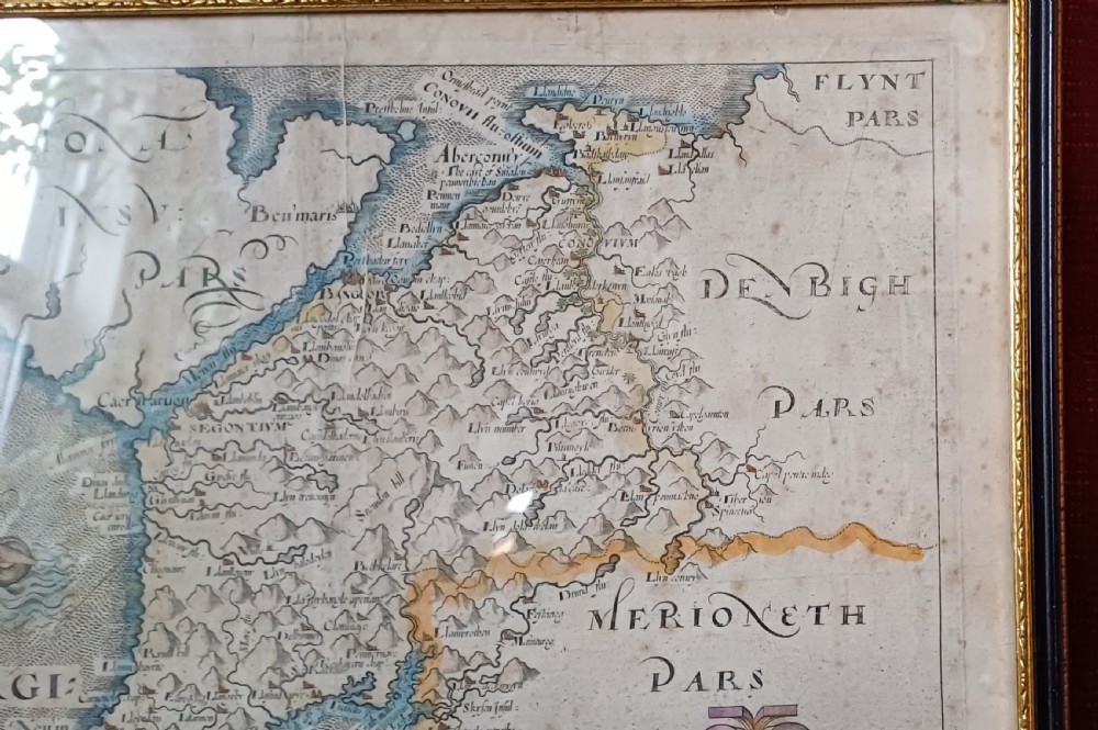 A framed 17th-century hand-coloured map of Caernarvonshire featuring a decorative cartouche, compass rose, and sea monster illustration. View VIII