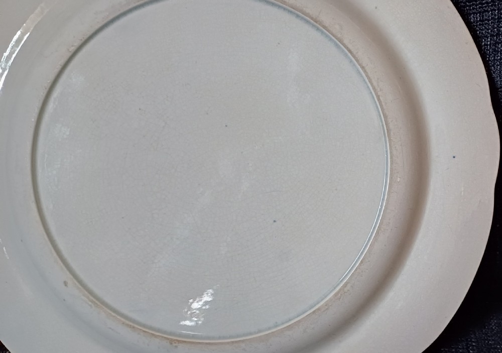 A circular blue and white transfer-printed earthenware plate featuring a central pastoral scene of figures near beehives surrounded by a floral and animal vignette border. View XIII
