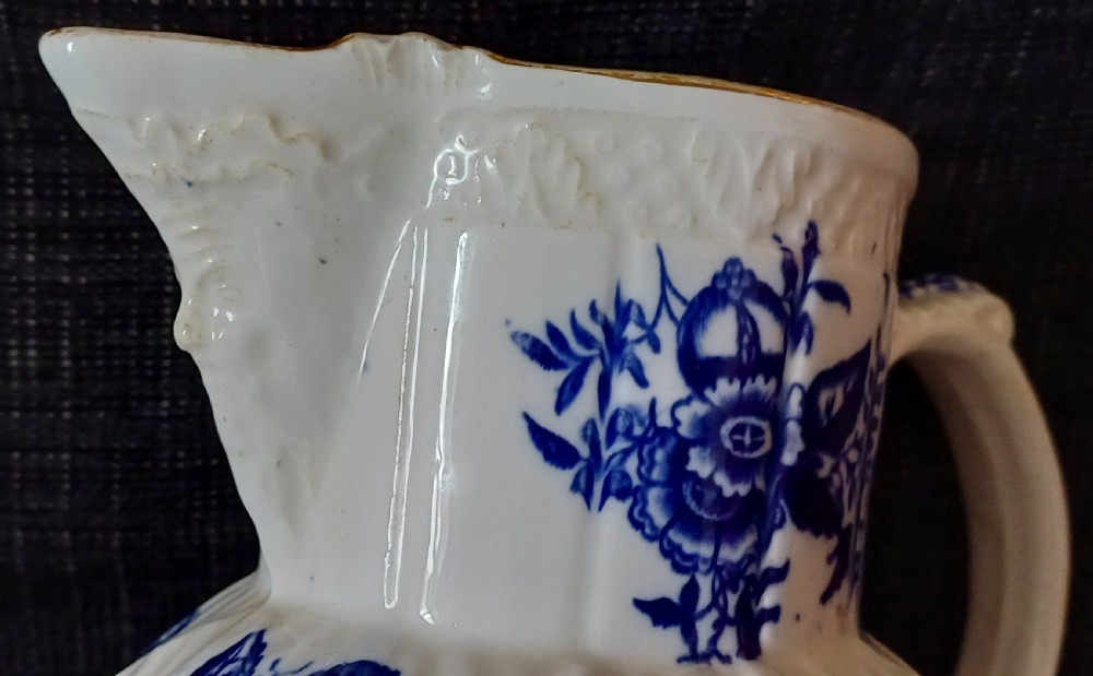 A Georgian porcelain jug featuring blue transferware floral and pine cone patterns with a moulded mask spout and ribbed body. View XI
