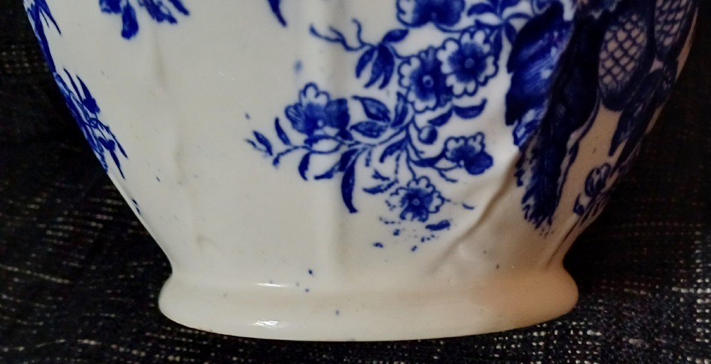 A Georgian porcelain jug featuring blue transferware floral and pine cone patterns with a moulded mask spout and ribbed body. View XV