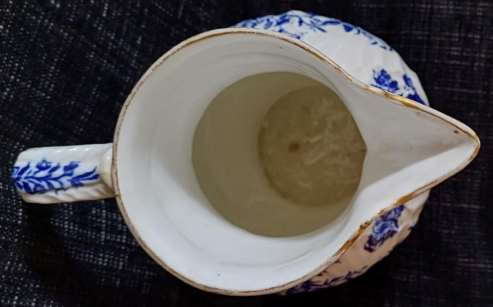 A Georgian porcelain jug featuring blue transferware floral and pine cone patterns with a moulded mask spout and ribbed body. View XVI