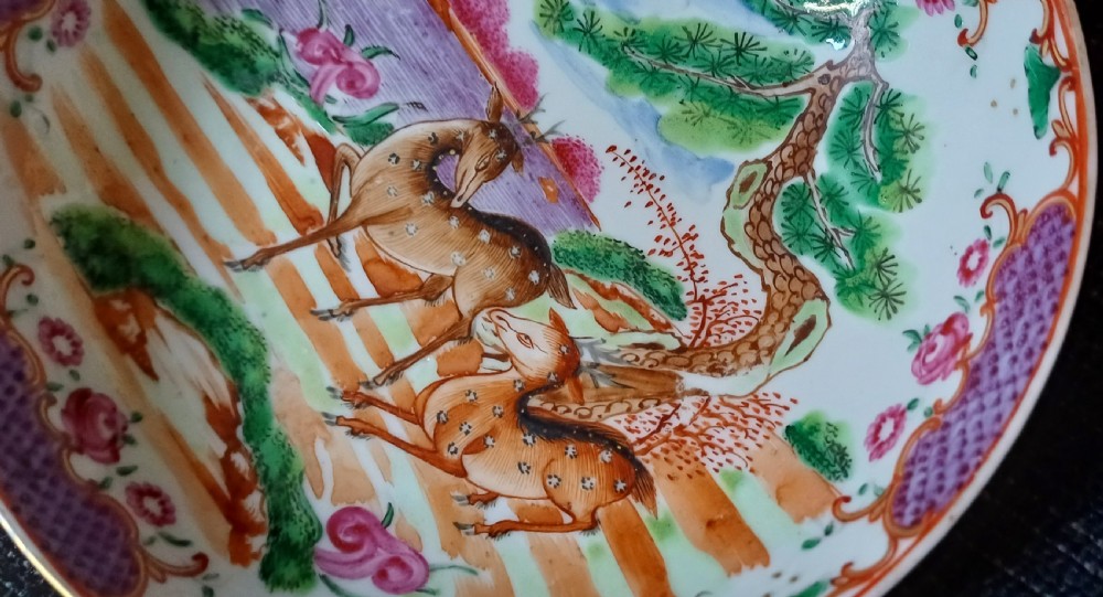 A circular 18th-century Chinese export porcelain saucer hand-painted with deer, a pine tree, and a flying bat motif within a purple lattice border. View XVI