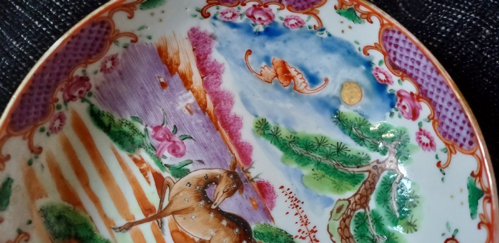 A circular 18th-century Chinese export porcelain saucer hand-painted with deer, a pine tree, and a flying bat motif within a purple lattice border. View XIX