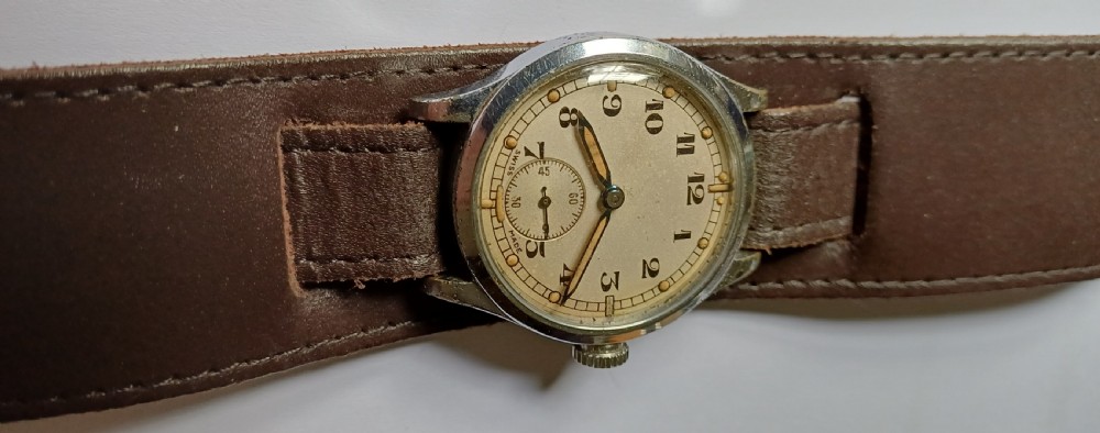 A vintage 1940s military wristwatch with a cream dial, Arabic numerals, sub-seconds display, and a wide brown leather cuff strap.