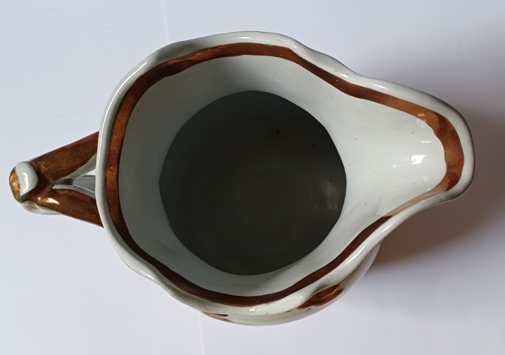 An antique off-white ironstone jug decorated with copper lustre relief leaves around the rim and handle, featuring painted botanical flowers on the body. View XI