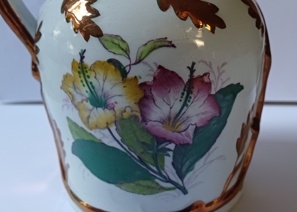 An antique off-white ironstone jug decorated with copper lustre relief leaves around the rim and handle, featuring painted botanical flowers on the body. View XII