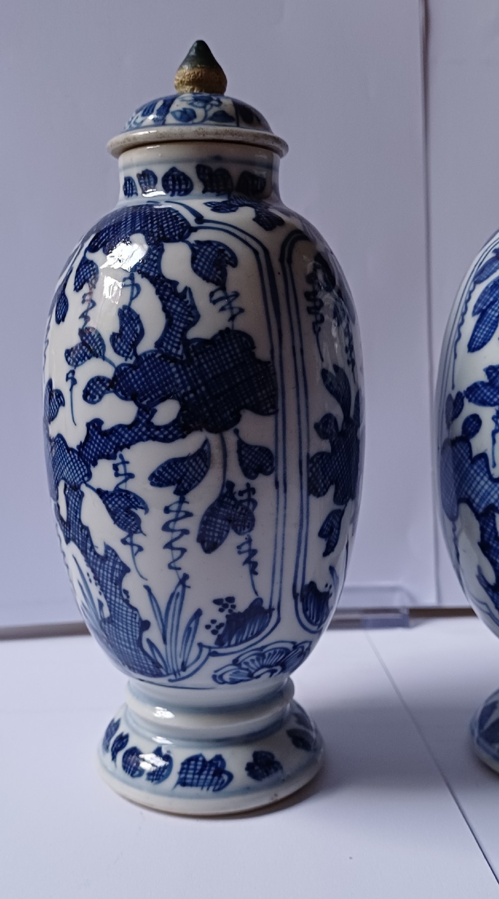A pair of antique Chinese Kangxi period ovoid porcelain jars with fitted lids, decorated with hand-painted cobalt blue floral motifs on a white background. View IX
