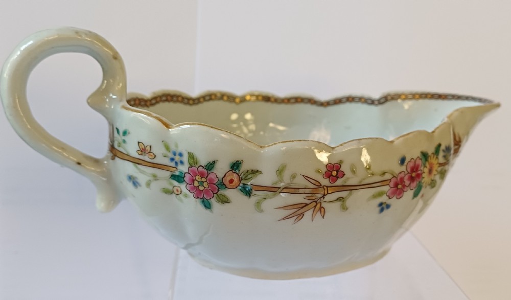 An 18th-century Chinese export famille rose porcelain sauce boat decorated with a hand-painted crest, coat of arms, and floral motifs. View IX