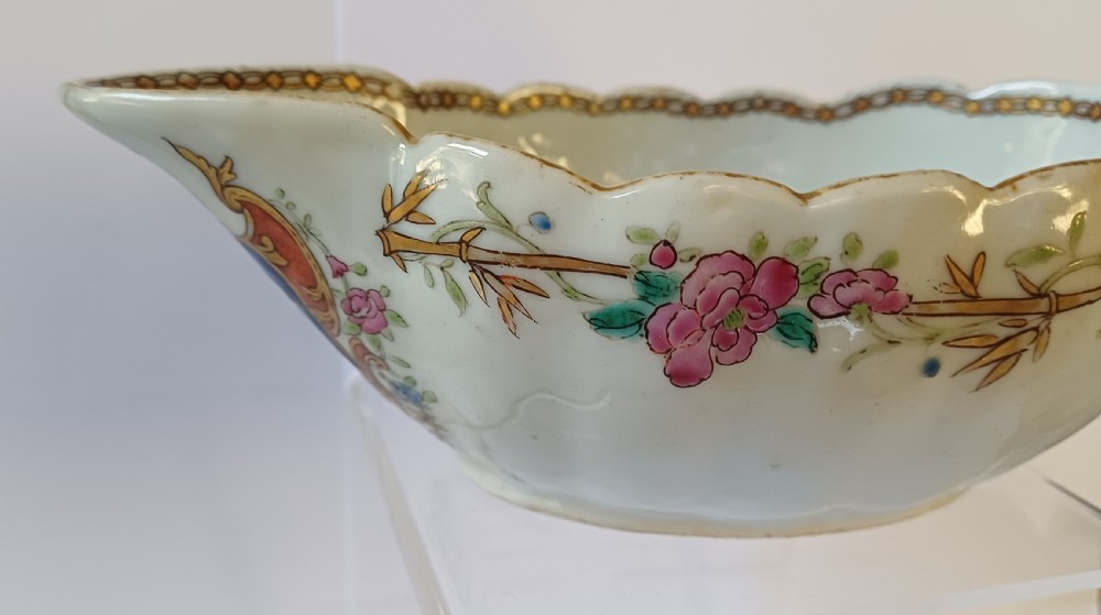 An 18th-century Chinese export famille rose porcelain sauce boat decorated with a hand-painted crest, coat of arms, and floral motifs. View X