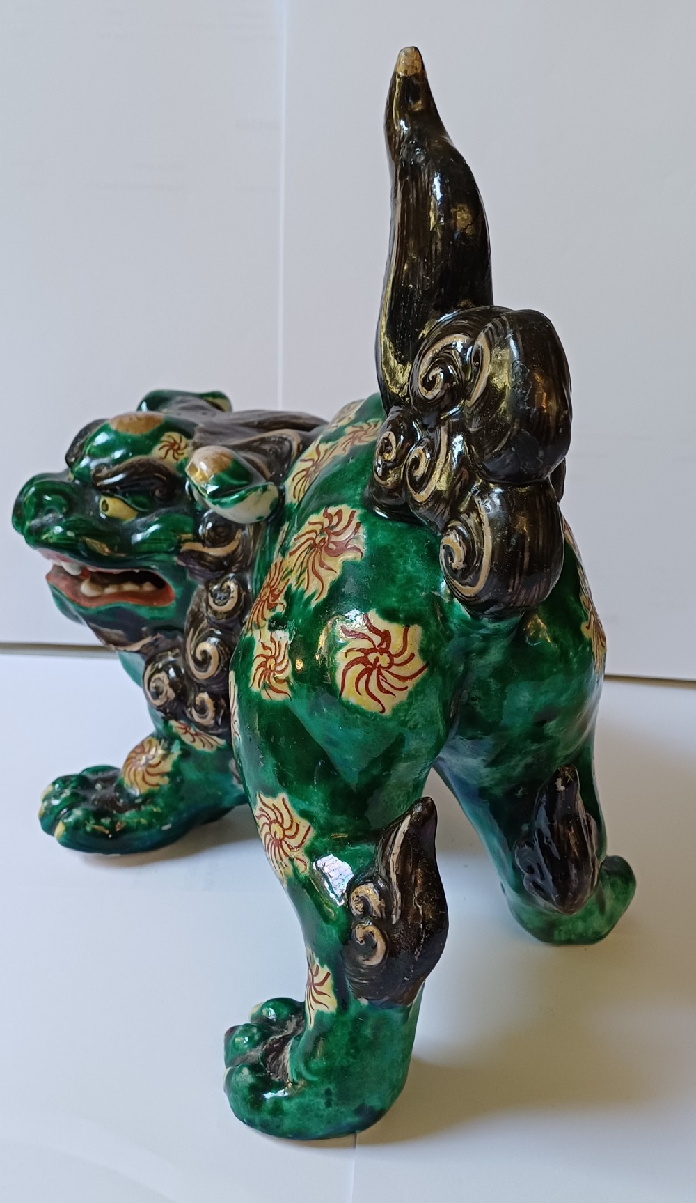 A Japanese Kutani glazed porcelain Shishi lion featuring a vibrant emerald green body decorated with gold floral motifs and a dark scrolling mane. View IV