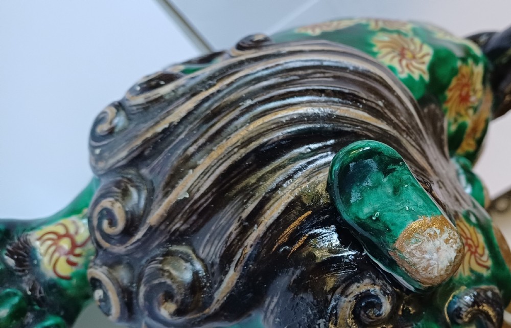 A Japanese Kutani glazed porcelain Shishi lion featuring a vibrant emerald green body decorated with gold floral motifs and a dark scrolling mane. View XI