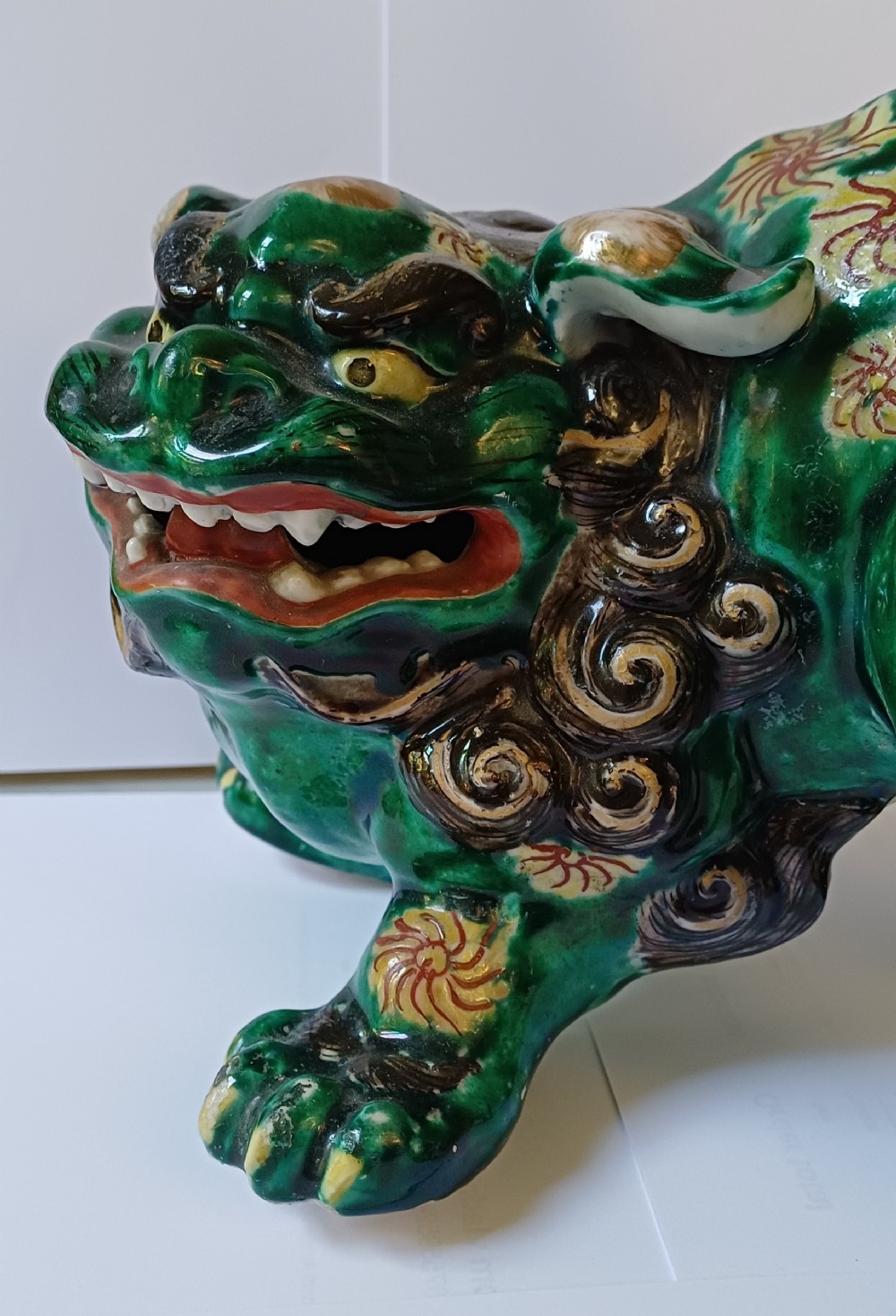 A Japanese Kutani glazed porcelain Shishi lion featuring a vibrant emerald green body decorated with gold floral motifs and a dark scrolling mane. View XVII