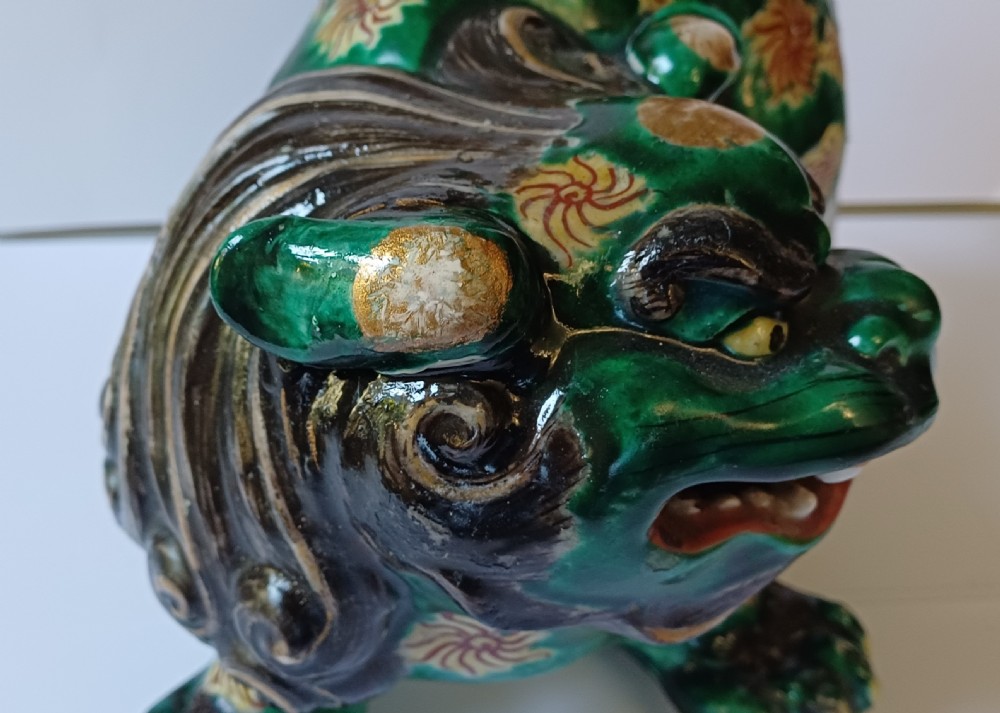 A Japanese Kutani glazed porcelain Shishi lion featuring a vibrant emerald green body decorated with gold floral motifs and a dark scrolling mane. View XIX