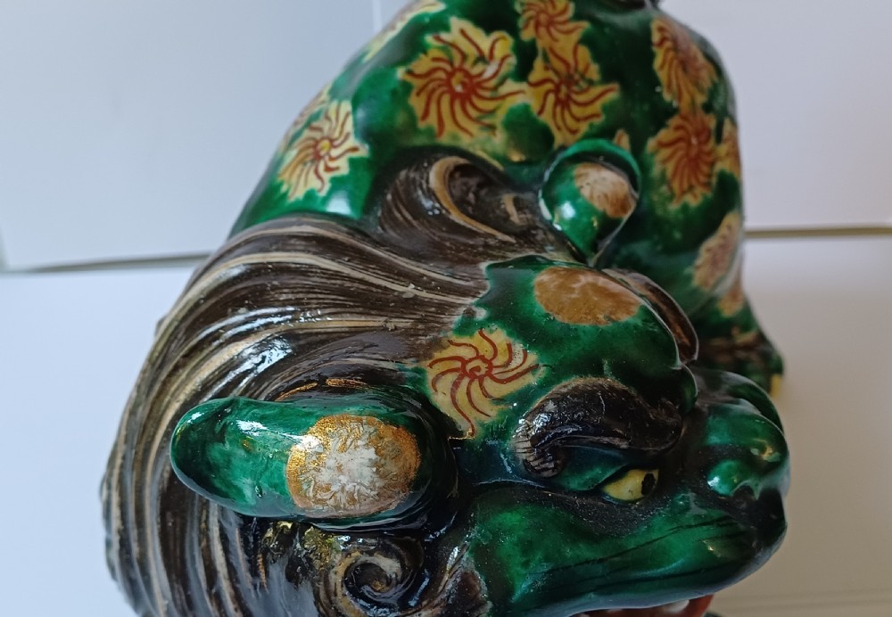 A Japanese Kutani glazed porcelain Shishi lion featuring a vibrant emerald green body decorated with gold floral motifs and a dark scrolling mane. View XX