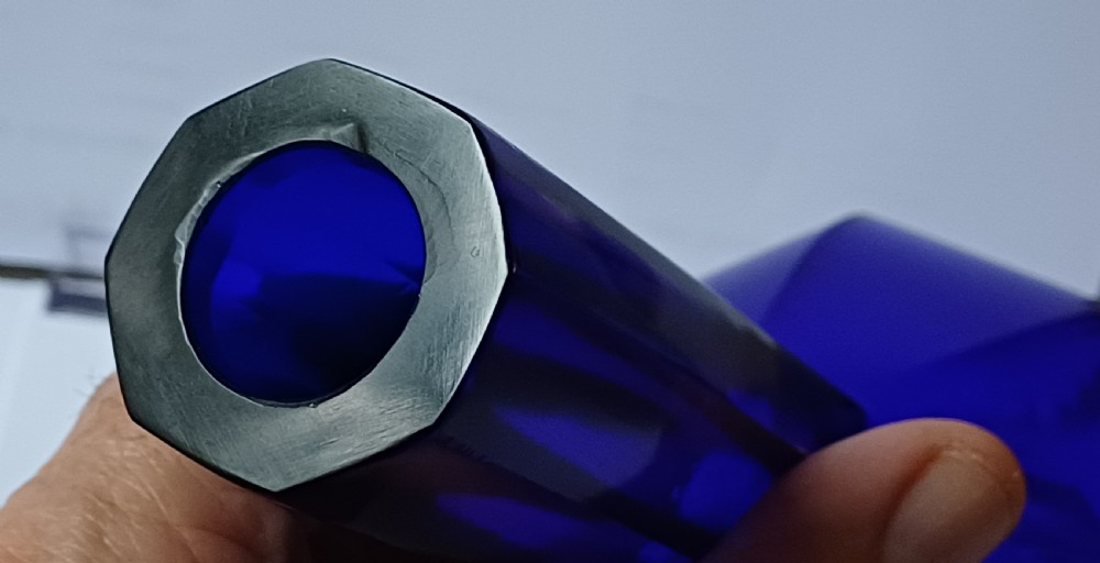 A cobalt blue glass bottle vase featuring an octagonal faceted globular body and a tall matching octagonal neck. View X