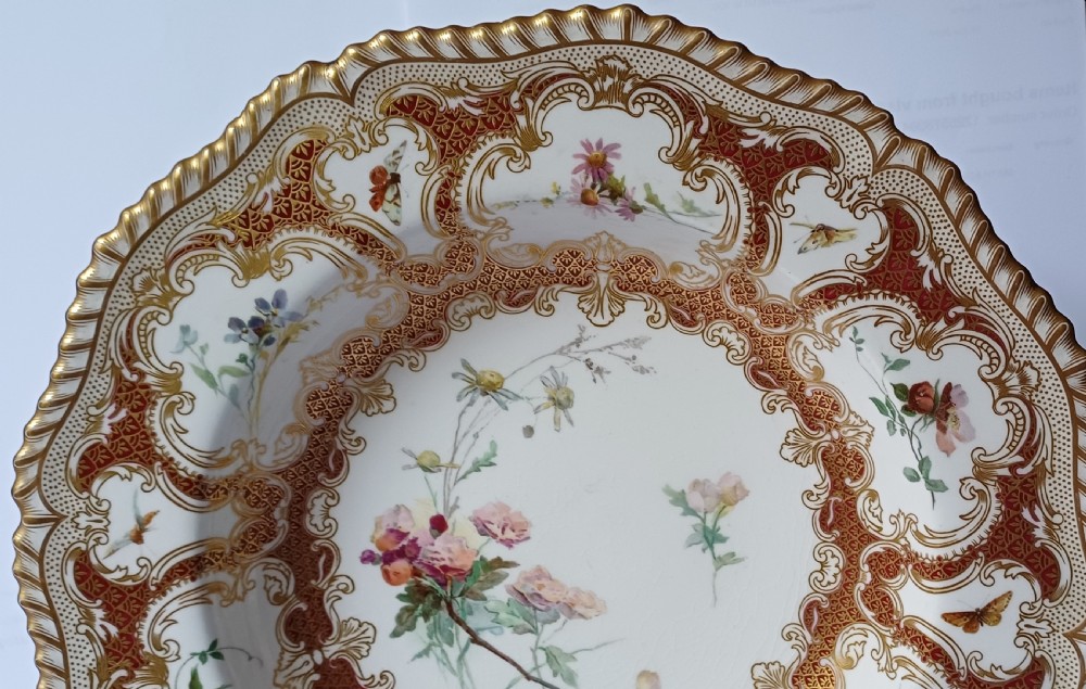 A circular late-Victorian Royal Worcester porcelain soup dish featuring hand-painted botanical floral and insect motifs enclosed within elaborate red and gold gilded rococo scroll borders. View III