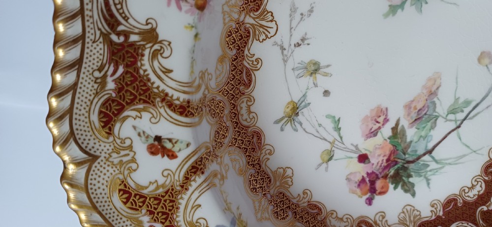 A circular late-Victorian Royal Worcester porcelain soup dish featuring hand-painted botanical floral and insect motifs enclosed within elaborate red and gold gilded rococo scroll borders. View VIII