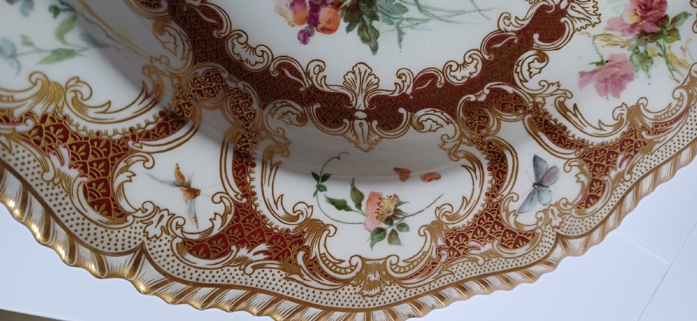 A circular late-Victorian Royal Worcester porcelain soup dish featuring hand-painted botanical floral and insect motifs enclosed within elaborate red and gold gilded rococo scroll borders. View IX