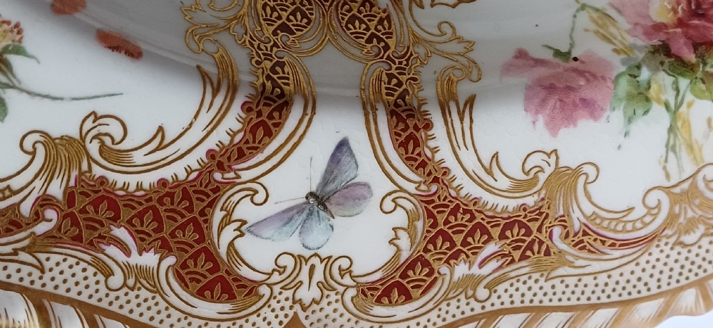 A circular late-Victorian Royal Worcester porcelain soup dish featuring hand-painted botanical floral and insect motifs enclosed within elaborate red and gold gilded rococo scroll borders. View XI
