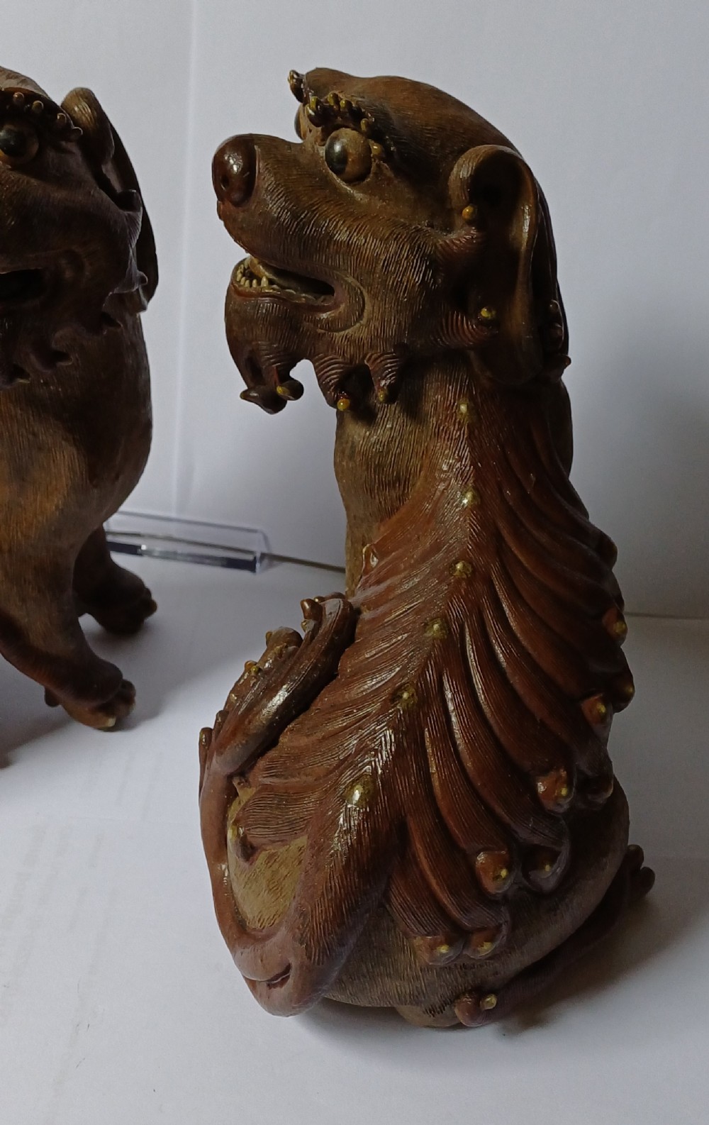 A pair of antique brown glazed ceramic Chinese Shiwan Buddhistic lion dogs depicted sitting upright with open mouths and detailed carved fur. View V