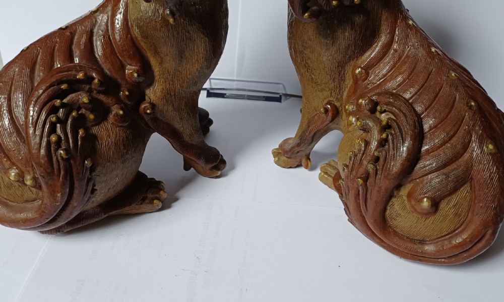 A pair of antique brown glazed ceramic Chinese Shiwan Buddhistic lion dogs depicted sitting upright with open mouths and detailed carved fur. View XII