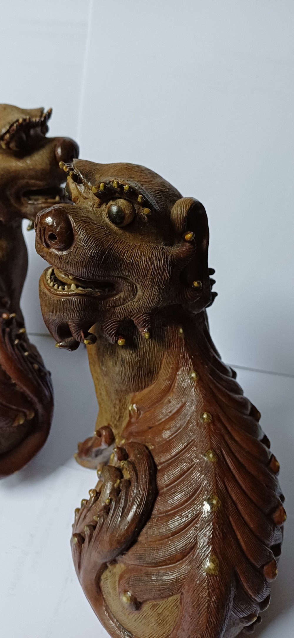 A pair of antique brown glazed ceramic Chinese Shiwan Buddhistic lion dogs depicted sitting upright with open mouths and detailed carved fur. View XX