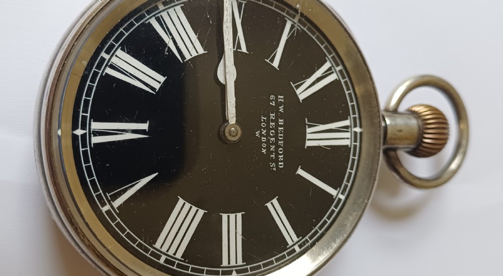 An oversized Edwardian silver-cased pocket watch featuring a black dial with white Roman numerals and a brass winding crown. View II
