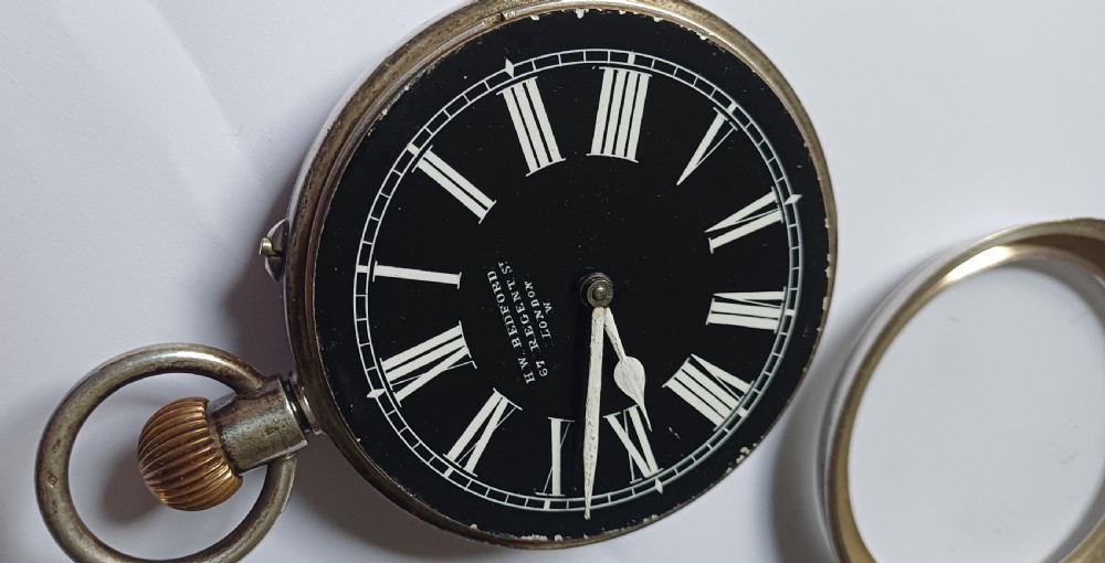 An oversized Edwardian silver-cased pocket watch featuring a black dial with white Roman numerals and a brass winding crown. View XI