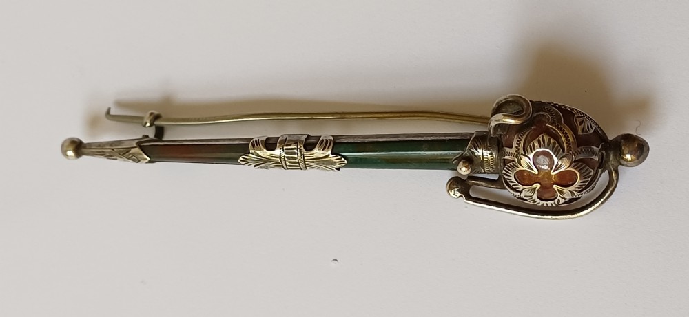 An antique silver kilt pin crafted in the shape of a Scottish basket-hilted broadsword inlaid with green and brown polished agate stones. View III