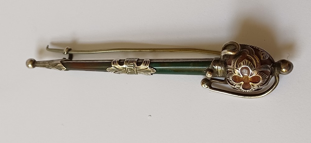 An antique silver kilt pin crafted in the shape of a Scottish basket-hilted broadsword inlaid with green and brown polished agate stones. View IV