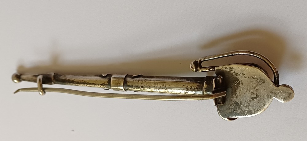 An antique silver kilt pin crafted in the shape of a Scottish basket-hilted broadsword inlaid with green and brown polished agate stones. View V