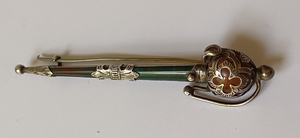 An antique silver kilt pin crafted in the shape of a Scottish basket-hilted broadsword inlaid with green and brown polished agate stones. View VI