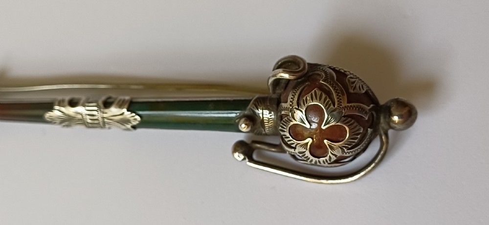 An antique silver kilt pin crafted in the shape of a Scottish basket-hilted broadsword inlaid with green and brown polished agate stones. View VIII