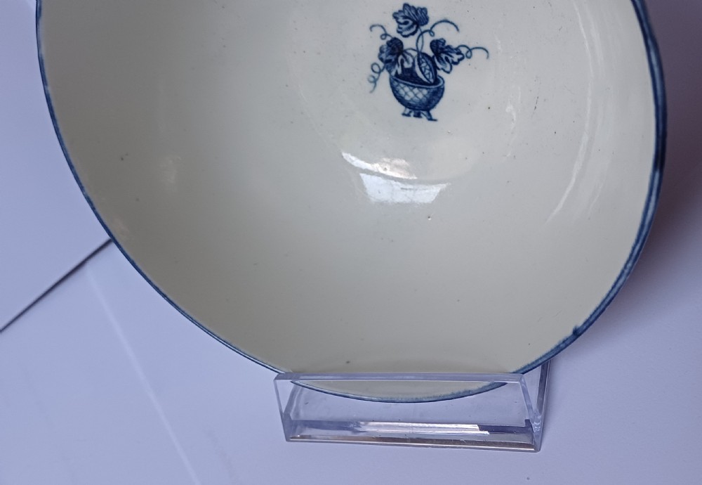 An eighteenth-century circular soft-paste porcelain bowl decorated with a hand-painted chinoiserie scene in underglaze blue on a cream background. View IX