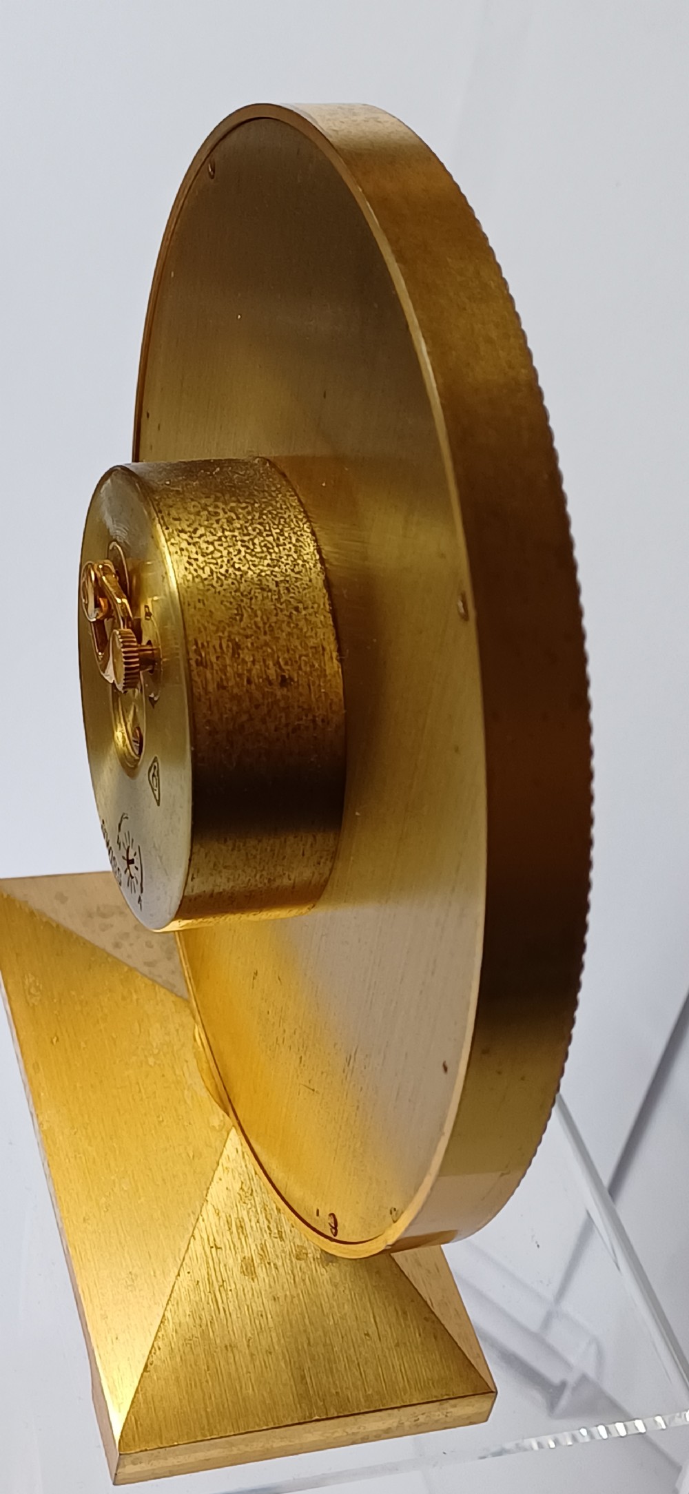 A mid-century Imhof gilt brass desk clock featuring a round textured gold dial with Roman numerals and a faceted rectangular pedestal base. View X