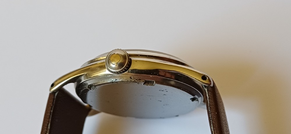A vintage 1950s Omega wristwatch with a cream dial, gold hour markers, stainless steel case, and a smooth brown leather strap. View III